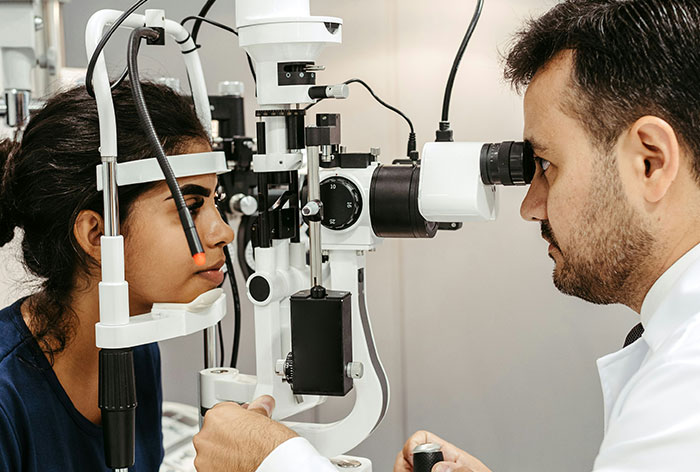 Ophthalmologist examining patient’s eyes using medical equipment for downplayed medical conditions and procedures.