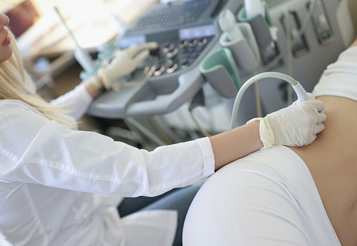 Medical professional performing ultrasound on patient, illustrating downplayed medical conditions and procedures.