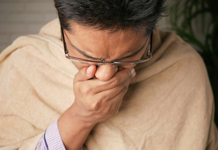 Man covering mouth and nose while feeling unwell, representing downplayed medical conditions and procedures.