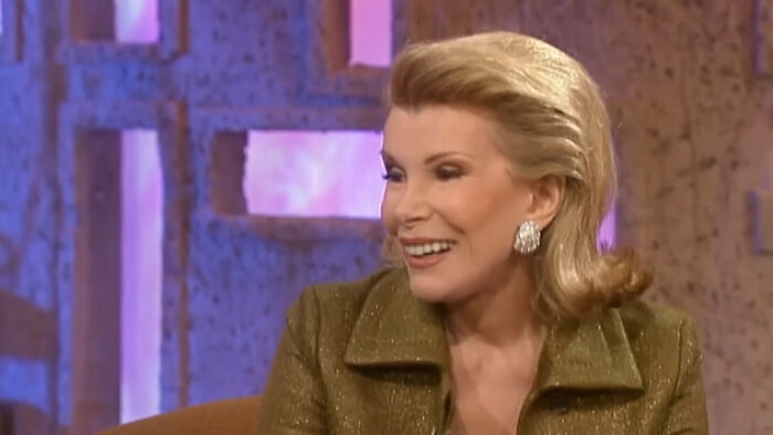Smiling woman with styled blonde hair wearing a green jacket and earrings during a heartwarming celebrity encounter interview.