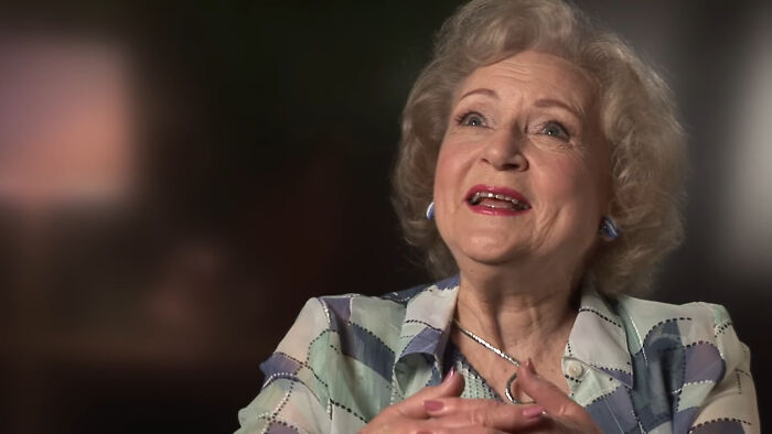 Elderly woman smiling warmly in an interview setting, sharing heartwarming celebrity encounters and memorable moments.