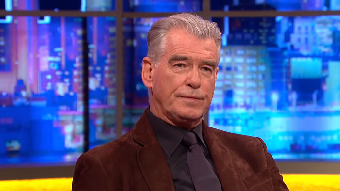 Actor in a brown jacket and black tie during a TV interview, related to heartwarming celebrity encounters shared by netizens.