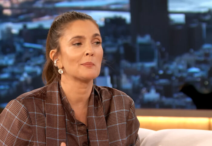 Woman in plaid jacket sharing a heartwarming celebrity encounter in a cozy interview setting with cityscape background