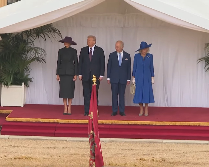 Melania Trump and former President Trump stand with British royal family members on a ceremonial stage outdoors.