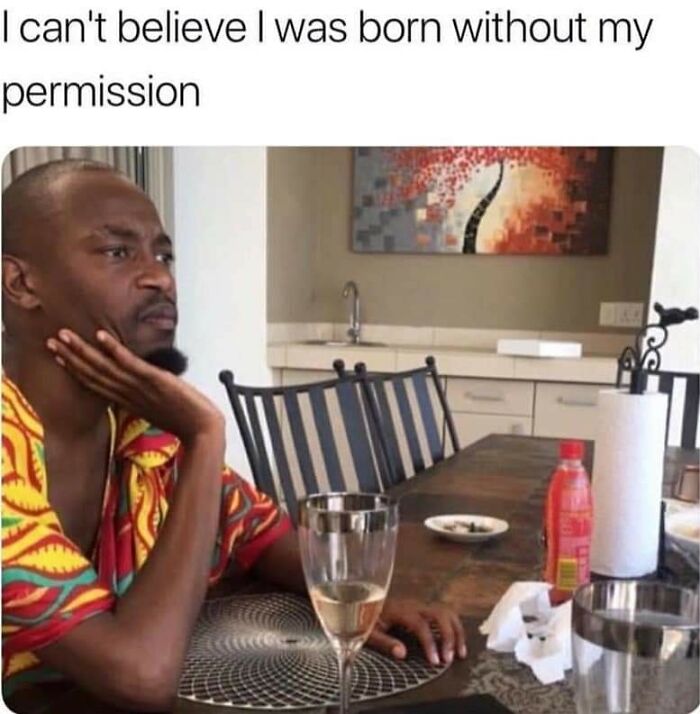 Man in colorful shirt sitting at table with drink, looking thoughtful, caption reads about being born without permission – mental health meme.