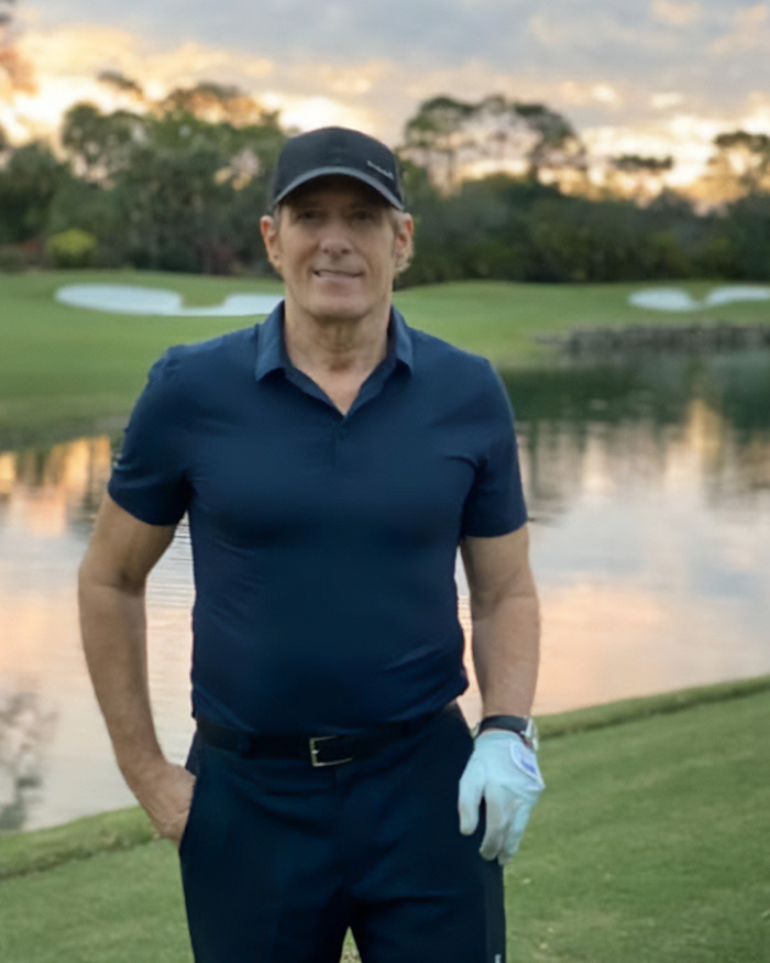 Man in golf attire standing by a lake at sunset showing weird symptom before doctors shared heartbreaking diagnosis.