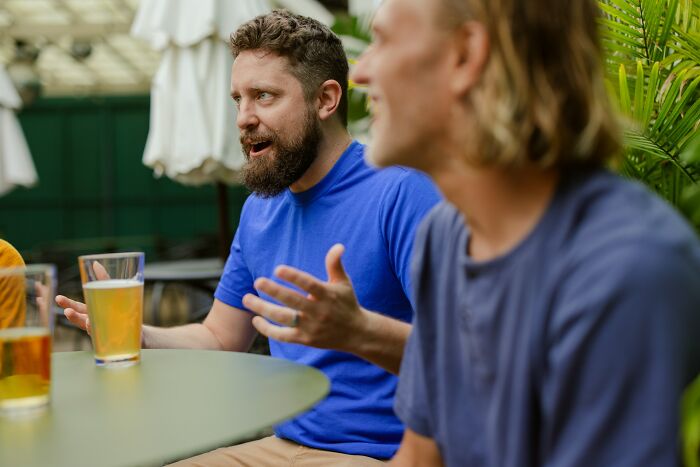 Two men in casual clothes having a lively conversation over drinks, sharing relationship tips for happy marriages.