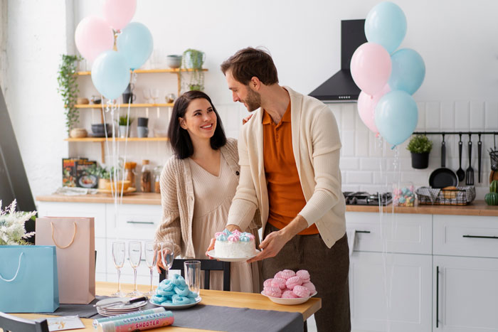 Couple celebrating at a baby shower with allergy-safe food and pastel balloon decorations in a bright kitchen setting. Couple celebrating at a baby shower with allergy-safe food and pastel balloon decorations in a bright kitchen setting.