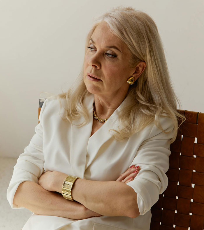 Unhappy middle-aged woman resembling unhinged MIL sitting with arms crossed, showing frustration and making demands.