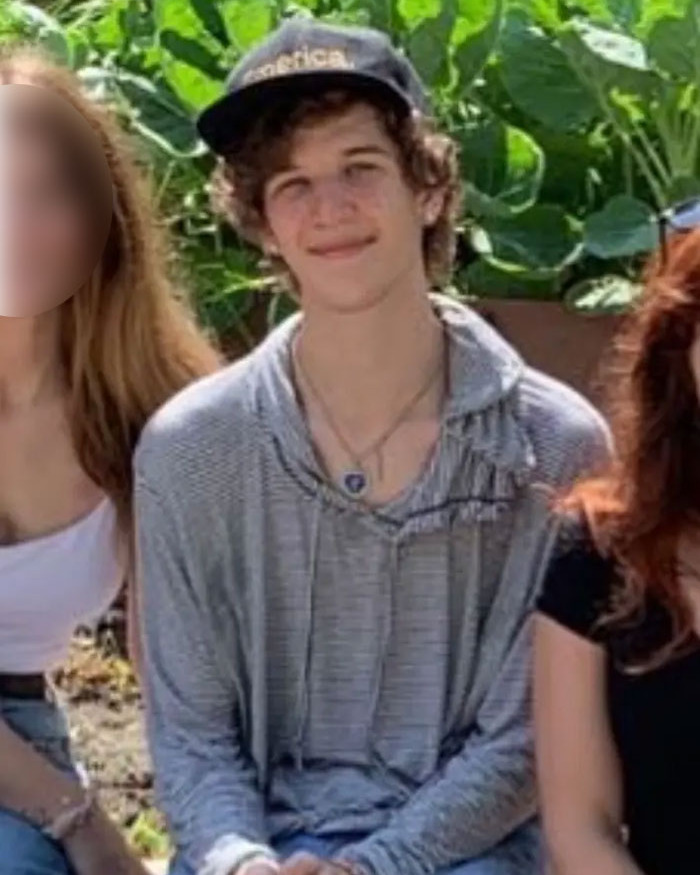 Young man wearing a cap and gray hoodie sitting outdoors with leafy green plants in the background, Minneapolis suspect&rsquo;s furry girlfriend
