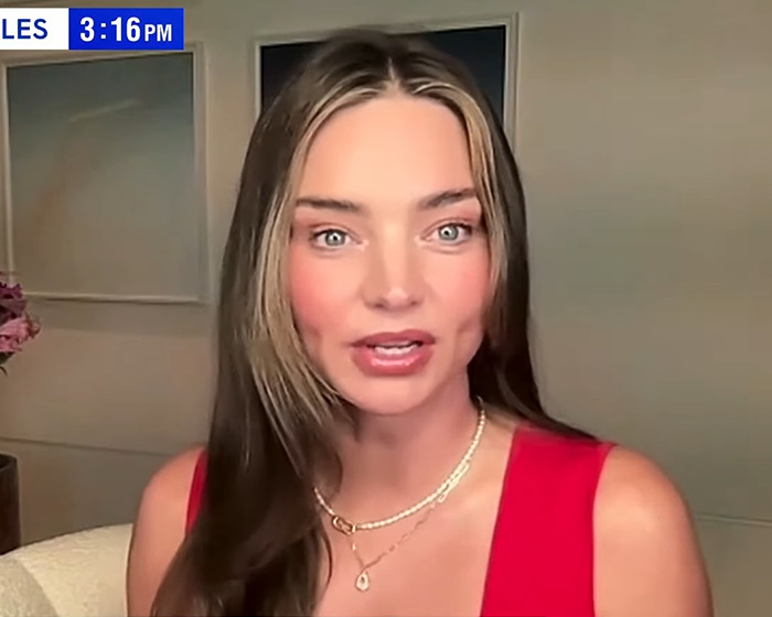 Miranda Kerr speaking in a red top, sharing her reaction on ex Orlando Bloom's breakup with Katy Perry during an interview.