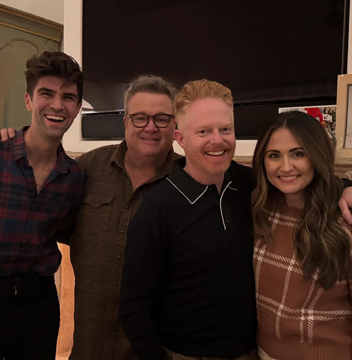 Eric Stonestreet and Jesse Tyler Ferguson smiling with friends in a casual indoor setting celebrating a special occasion.