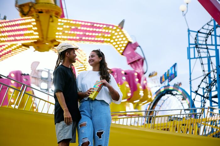 A happy couple enjoying time together at a colorful amusement park, symbolizing tips for a great relationship.