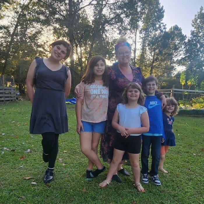 Mom of five with her children standing outdoors in a grassy area with trees in the background Mom of five with her children standing outdoors in a grassy area with trees in the background