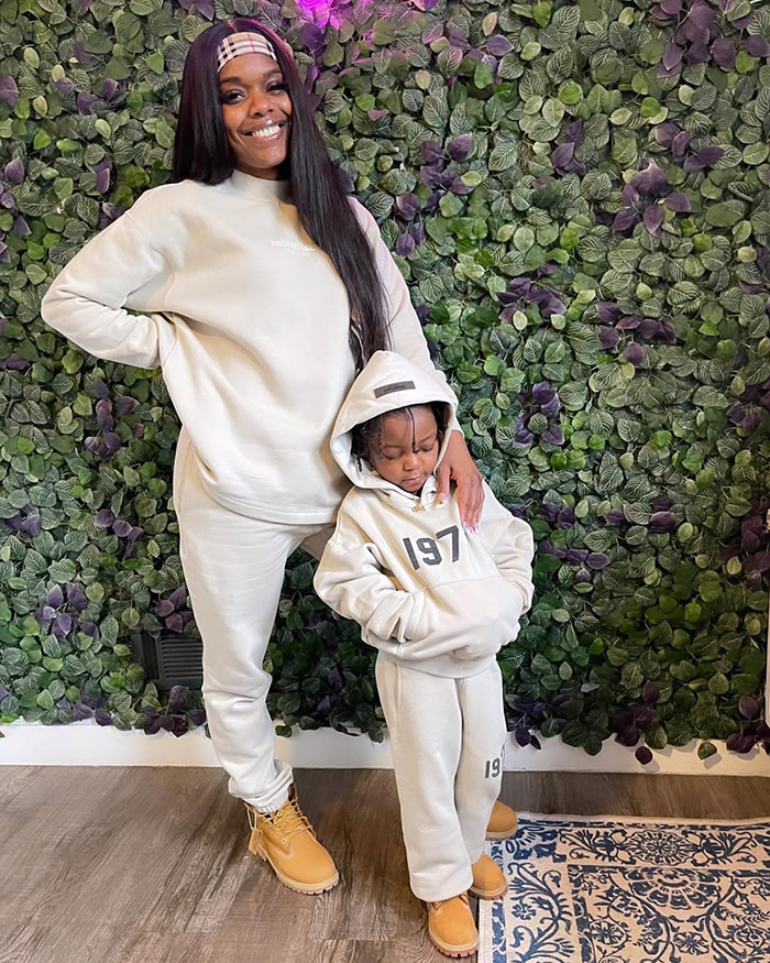 Woman and her son dressed in matching beige outfits standing in front of a green leafy wall, representing loving note in son's lunchbox story.