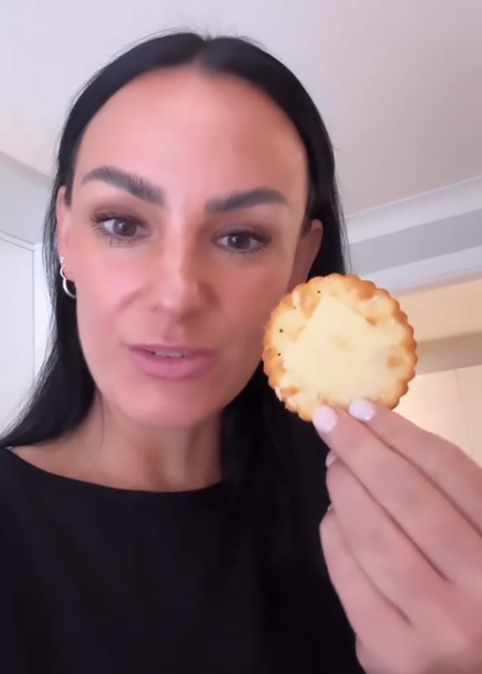 Furious mom holding a snack, reacting to son being banned from eating it at school by the teacher.
