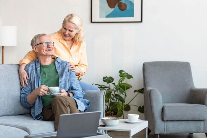 Smiling mature couple enjoying coffee at home, illustrating a relaxed moment in a mom retirement plan setting.