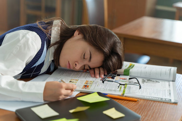 Young woman falls asleep on study materials, reflecting disappointment about study abroad opportunities and personal challenges. Young woman falls asleep on study materials, reflecting disappointment about study abroad opportunities and personal challenges.