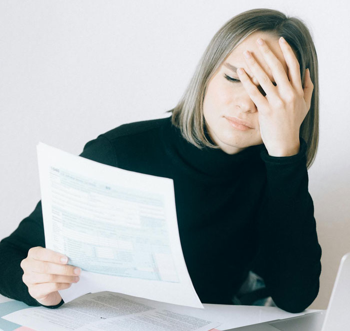 Woman learning the truth about why she never got to study abroad, looking stressed while holding papers at desk. Woman learning the truth about why she never got to study abroad, looking stressed while holding papers at desk.