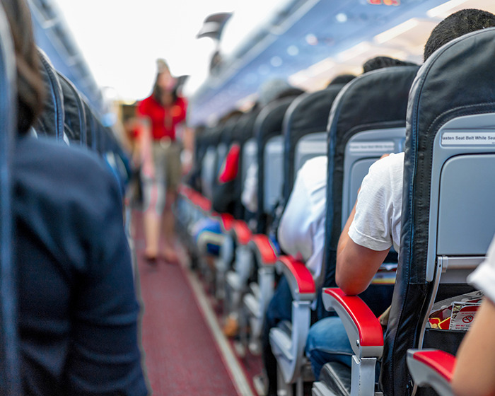 Passengers seated inside an airplane cabin with reclined seats, illustrating space issues and passenger discomfort. Passengers seated inside an airplane cabin with reclined seats, illustrating space issues and passenger discomfort.