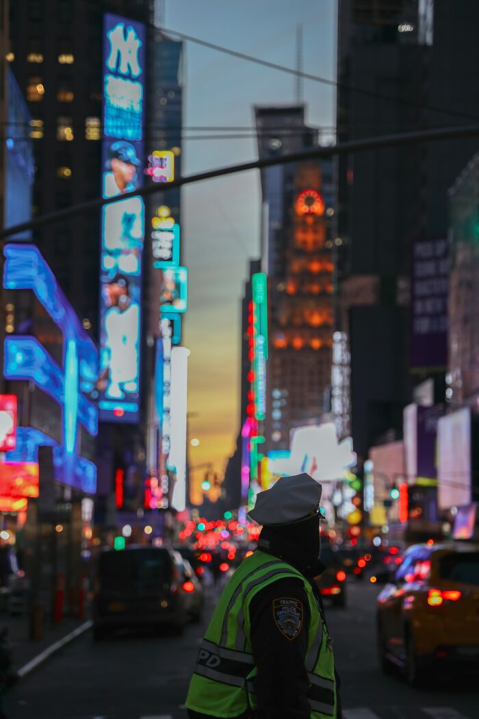 Police officer directing traffic at dusk in a busy city street with neon lights, related to school bullies topic.