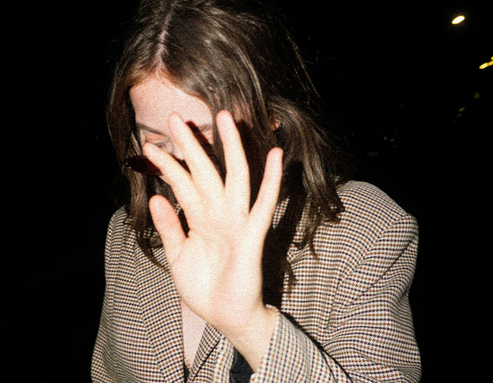 Woman covering face with hand in low light, illustrating TikTok moms discussing professions disliked for reasons.