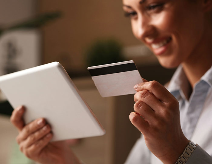Woman holding credit card and tablet, smiling while making an online purchase related to TikTok moms professions discussion