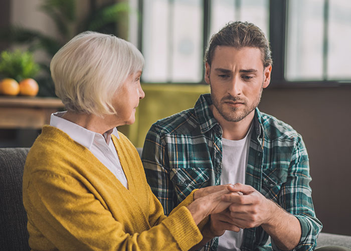 Mother and adult son having a serious conversation indoors, illustrating a mom admitting she hid college acceptance letters.