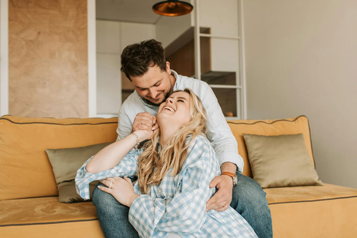 Couple sharing affectionate moment at home, illustrating themes of pregnancy and family support expectations.