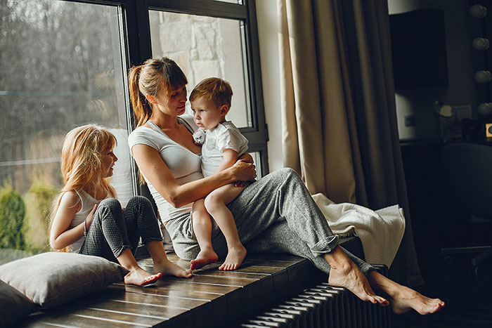 Woman sitting with two children by the window while her dogs are locked up during a house sit incident.