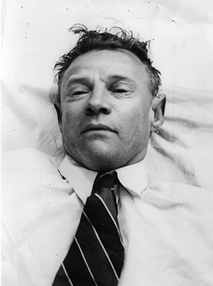 Black and white portrait of a man lying down in a shirt and tie, a photo that seems normal until you learn the mysteries behind it