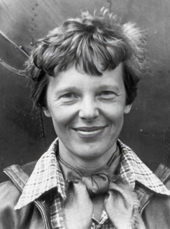 Black and white portrait of a smiling woman with short hair and a tied scarf, part of mysterious photos that seem normal.