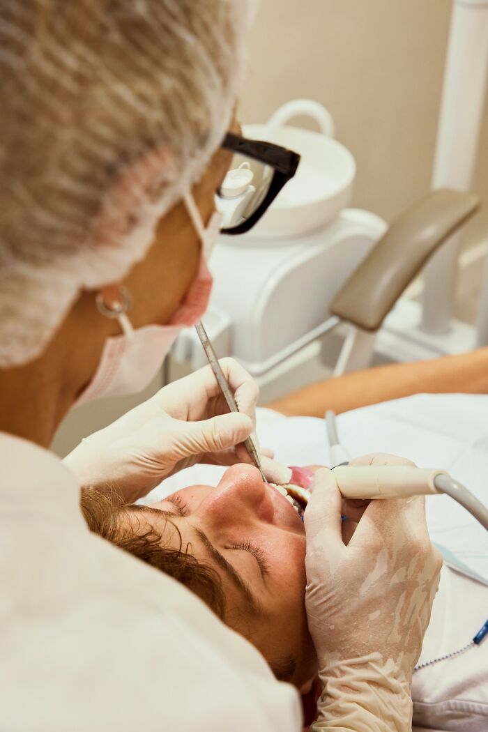 Doctor wearing gloves and mask treating patient in dental chair highlighting rare disease diagnosis.