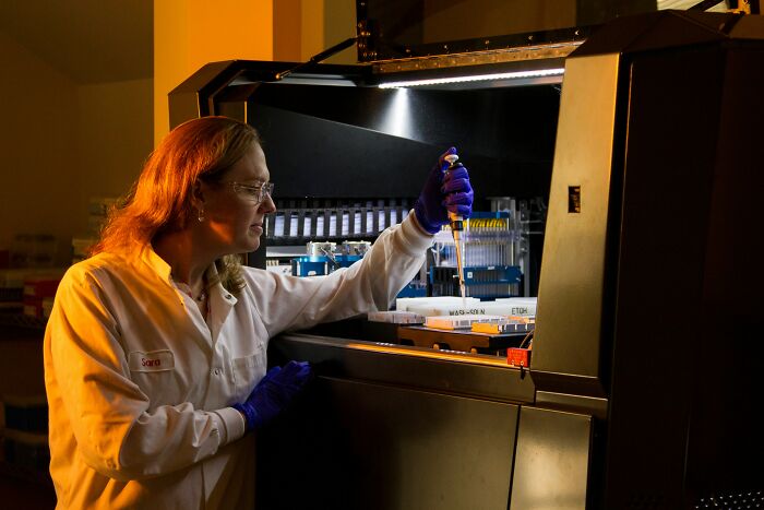 Female scientist in lab coat and gloves using medical equipment, highlighting patient attempts to fool doctors with lies.