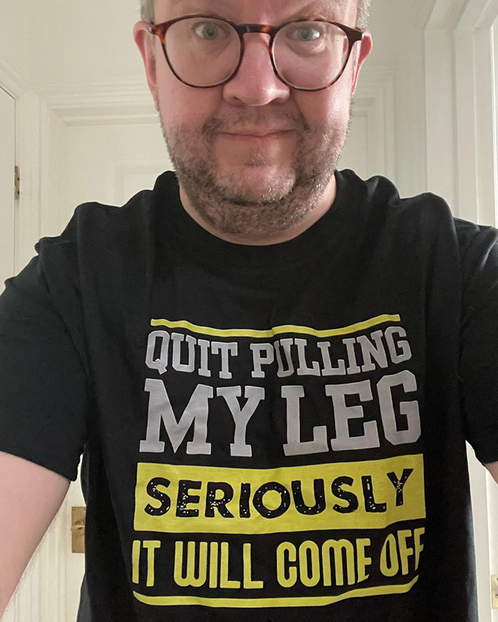 Man wearing glasses and a black shirt with text about legs, relating to surgeon who intentionally had own legs amputated. Man wearing glasses and a black shirt with text about legs, relating to surgeon who intentionally had own legs amputated.