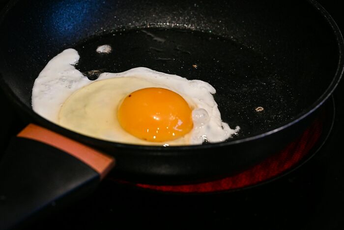 Fried egg cooking in a black pan on a stove, symbolizing quick moments related to fastest ways people get fired.