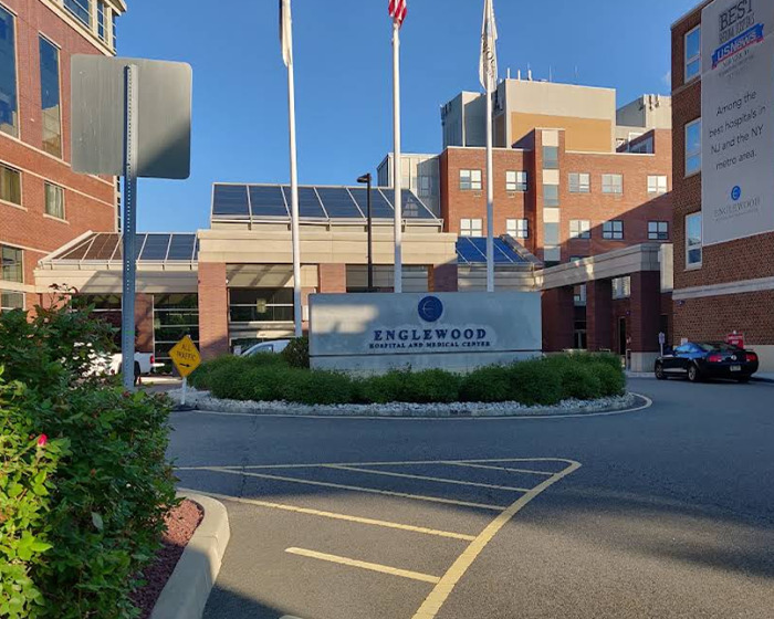Englewood Hospital and Medical Center exterior with flags and clear sky, related to nurse suspended for calling out doctor.