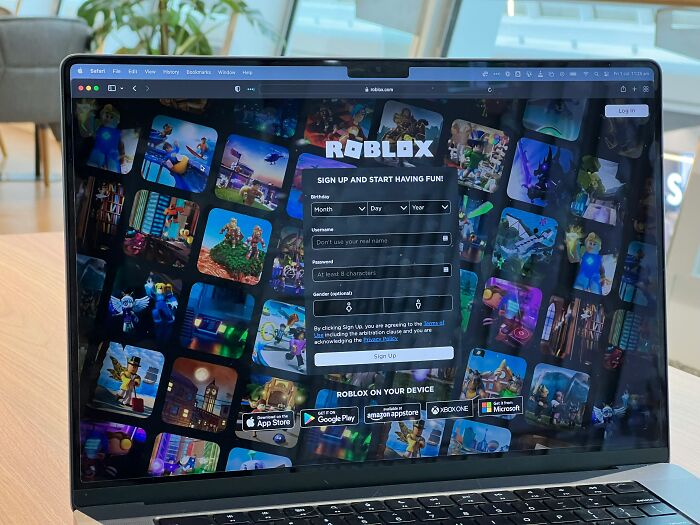 Laptop screen showing Roblox sign-up page with colorful game thumbnails, illustrating online engagement and digital entertainment.