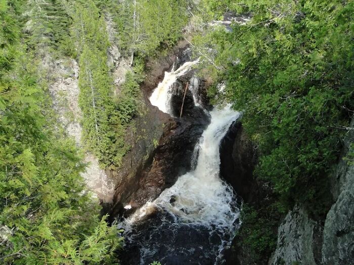 Waterfall flowing through rocky cliffs surrounded by dense forest in a photo with strange unexplained histories.