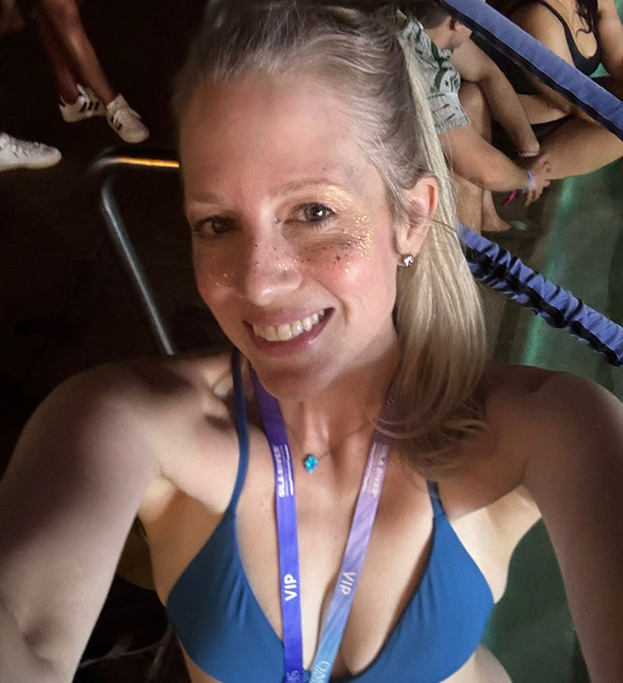 Woman smiling in a blue top wearing a VIP lanyard, representing woman shocked after best friend ends friendship over mom shorts.