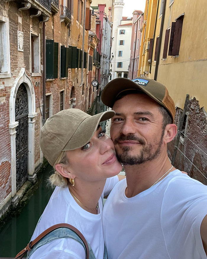 Miranda Kerr and Orlando Bloom taking a selfie in a scenic canal setting, sharing a close moment outdoors.