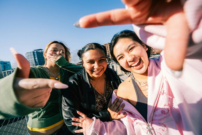 Three smiling Gen Z friends outdoors, capturing a playful moment reflecting typical Gen Z behavior and lifestyle. Three smiling Gen Z friends outdoors, capturing a playful moment reflecting typical Gen Z behavior and lifestyle.