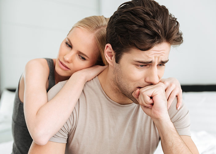 Young man looking distressed while woman comforts him, illustrating challenges of raising younger siblings and family conflict.