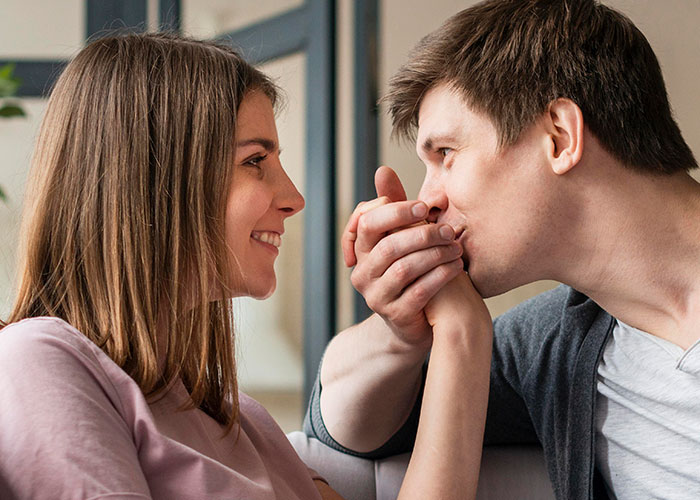 Young man showing affection to woman while sitting, symbolizing family challenges of parents making son raise siblings.