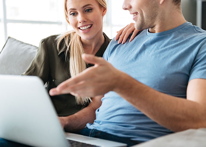 Young man and woman using laptop together, illustrating parents made son raise siblings concept in a home setting.