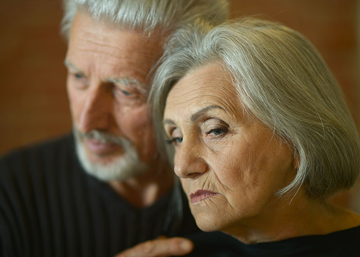 Elderly couple in somber mood, focusing on strained family dynamics involving son raising younger siblings.