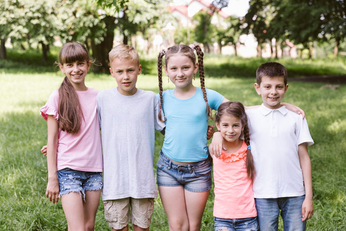Five smiling siblings standing together outdoors in a park, illustrating parents siblings Austria babysitting concept. Five smiling siblings standing together outdoors in a park, illustrating parents siblings Austria babysitting concept.