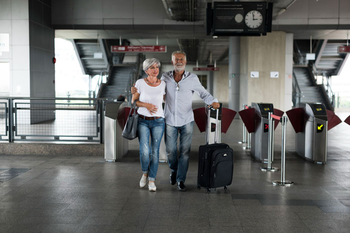 Older couple walking through a train station with luggage, illustrating parents siblings Austria babysitting and family travel. Older couple walking through a train station with luggage, illustrating parents siblings Austria babysitting and family travel.