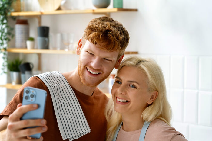 Young couple taking a selfie in a bright kitchen, smiling and enjoying the moment together.