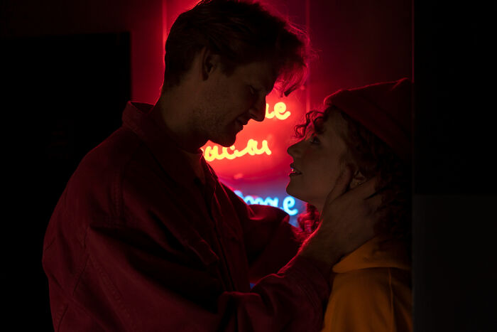 Couple sharing an intimate moment under red neon lights, highlighting partner connection.